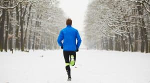 Man aan het hardlopen in een besneeuwd bos.