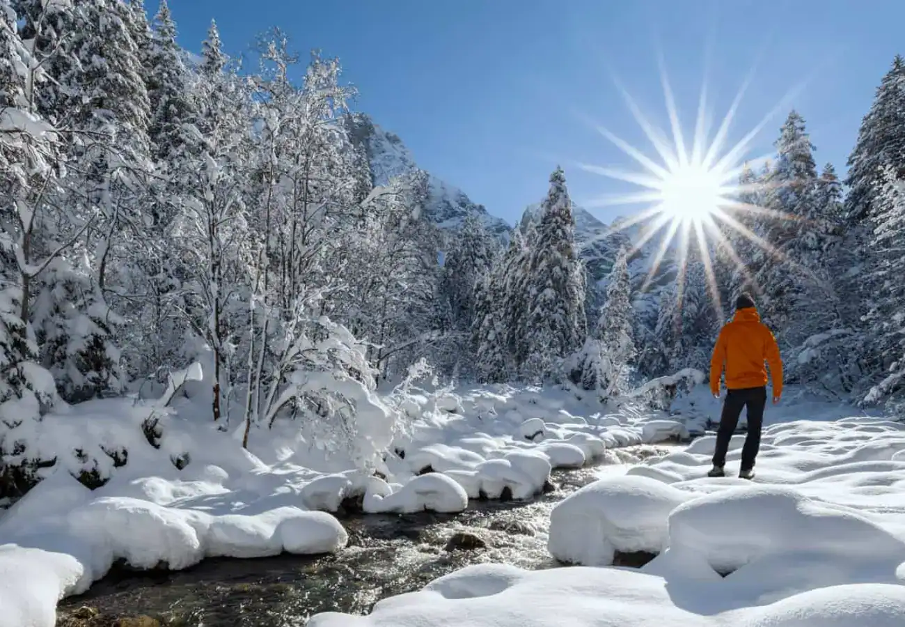 Personne marchant dans un paysage hivernal enneigé sous un soleil radieux