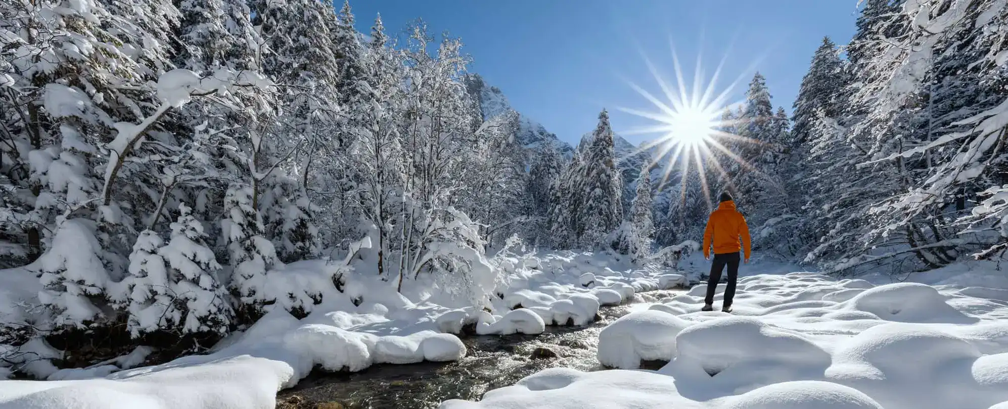Personne marchant dans un paysage hivernal enneigé sous un soleil radieux